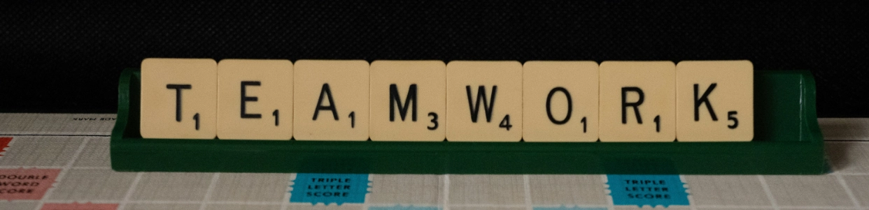 set de lettres de scrabble sur leur support écrivant le mot 'teamwork'